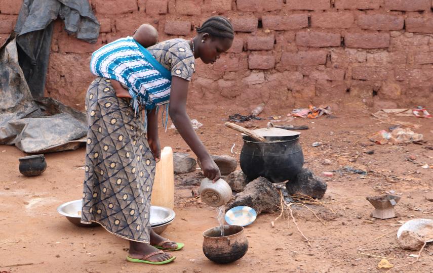 A woman cooks for a family of displaced people in Kongoussi